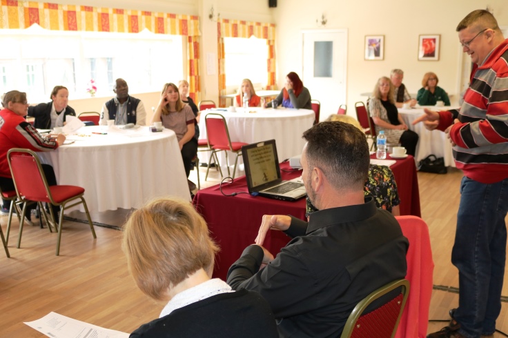 A group of people doing a presentation for three other groups.